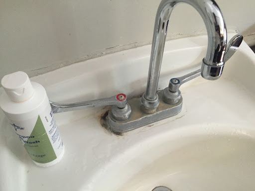 A close-up view of a bathroom sink with a chrome faucet and hygiene product.