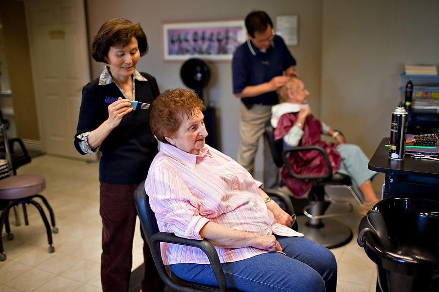 Senior citizens receiving haircuts at a salon specializing in elderly care.