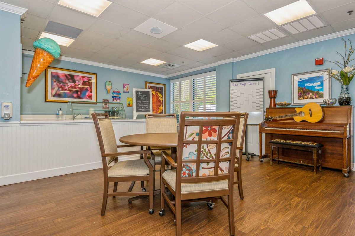 A cozy meeting room with a round table, chairs, and colorful artwork on blue walls.