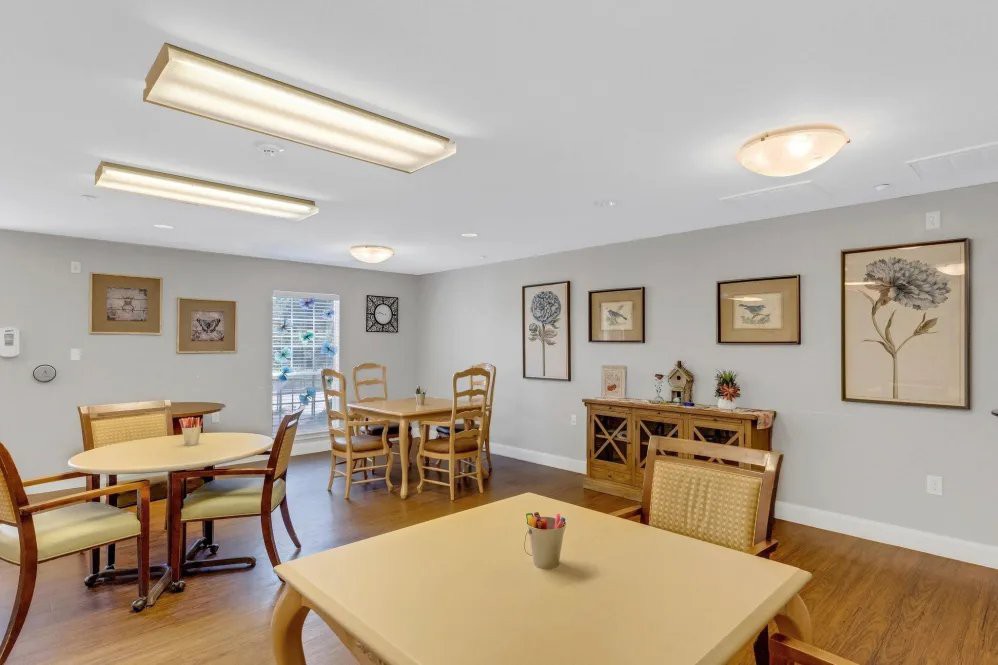 A bright and spacious dining area with neatly arranged tables and chairs, complemented by artwork on the walls.