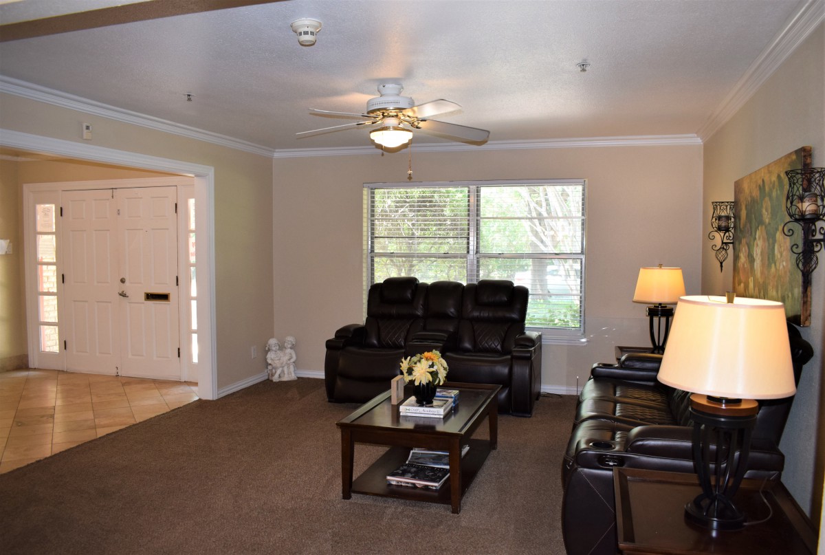 A cozy living room with leather sofas, a coffee table, and a ceiling fan.