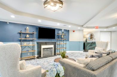 A modern living room with a cozy fireplace, blue accents, and stylish shelving.