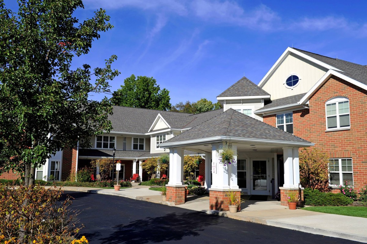The image shows the exterior of a residential building with a covered entrance and well-maintained landscaping.