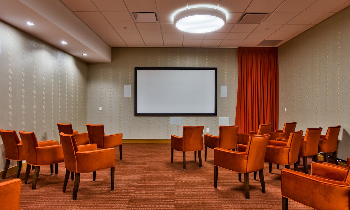 A modern conference room with comfortable seating and a large projector screen.