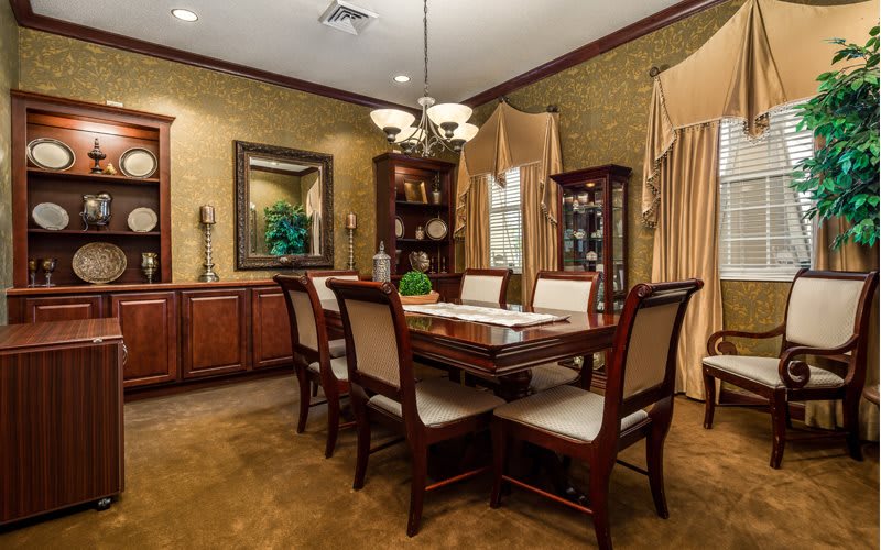 An elegant dining room featuring a wooden table with chairs, a chandelier, and classic decor.