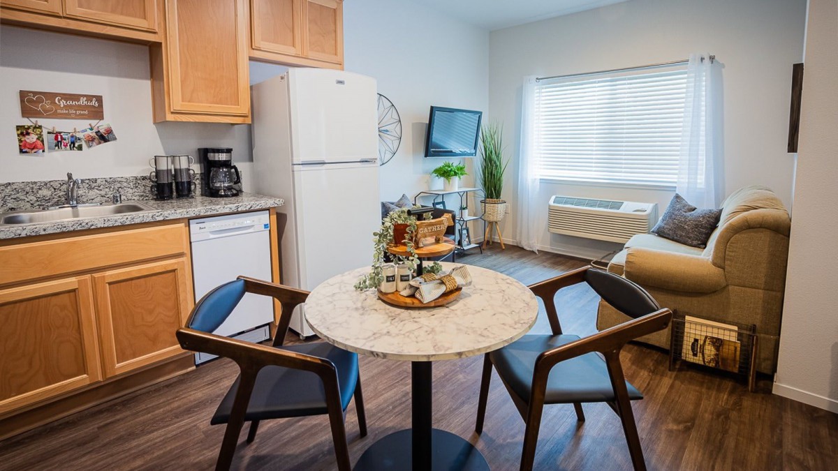 A cozy kitchen and dining area featuring a small round table with two chairs, modern appliances, and inviting decor.