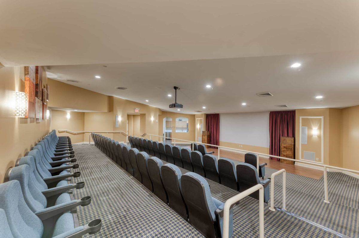 A small auditorium with tiered seating facing a projection screen.