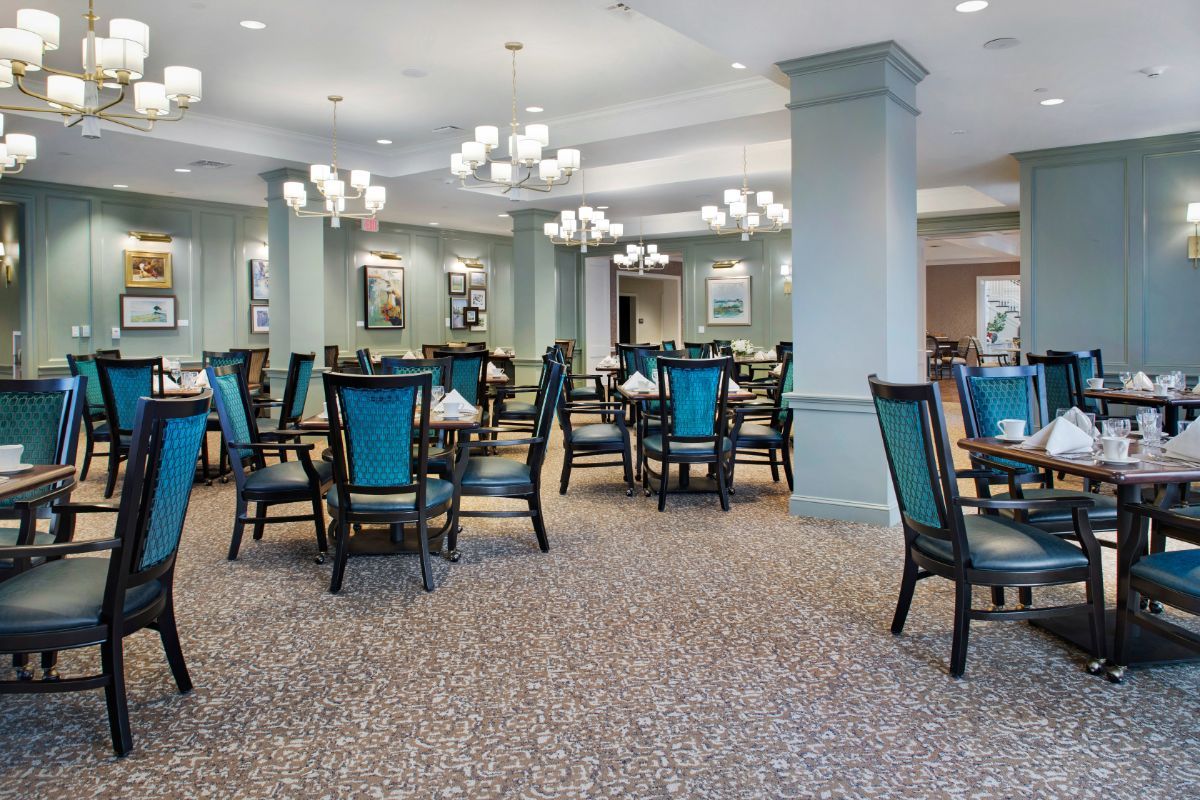 A spacious and elegantly designed dining room with multiple tables and chairs, featuring stylish lighting and decor.