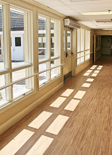 A bright hallway showcasing expansive windows that allow natural light to illuminate the wooden floor.