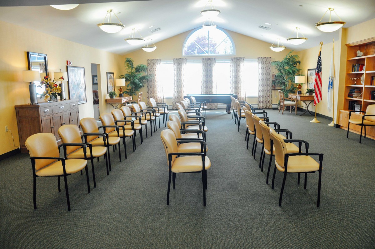 An empty waiting room with rows of chairs arranged neatly under soft lighting.