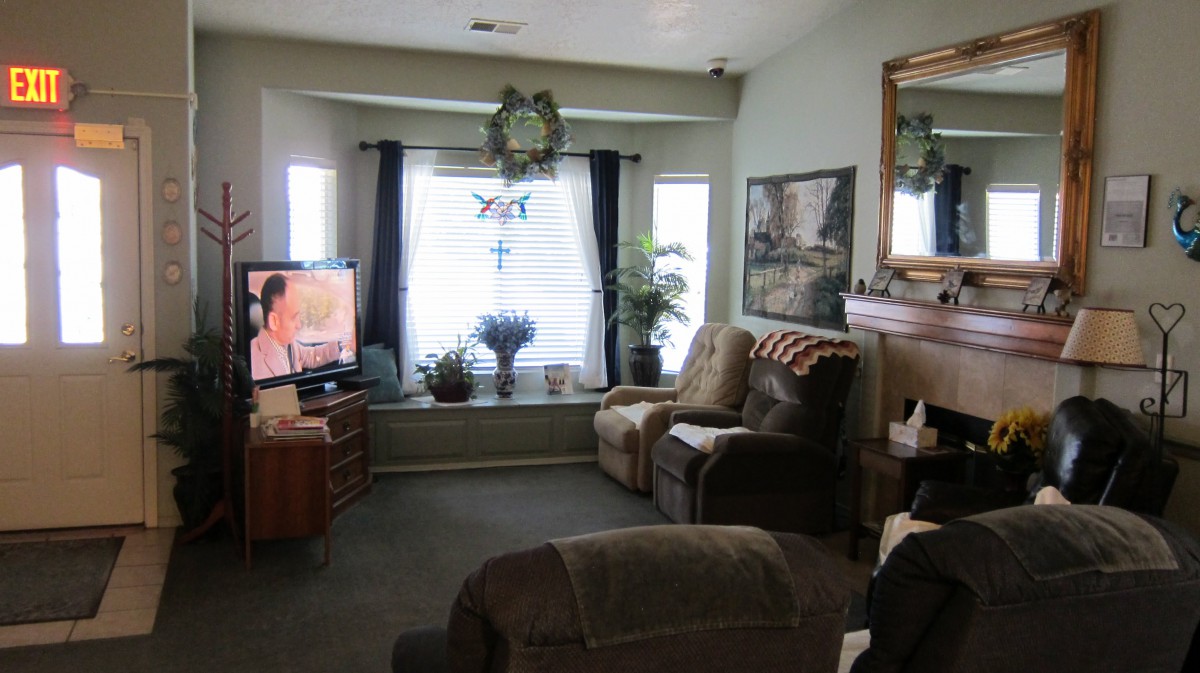 A cozy living room with comfortable seating, a television, and large windows letting in natural light.