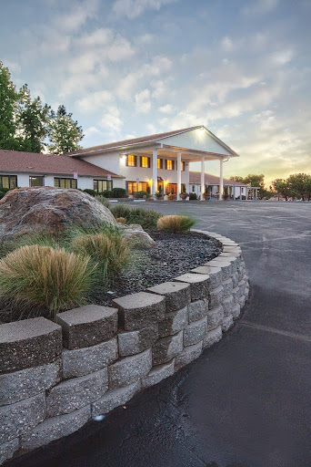 A welcoming hotel exterior during sunset, featuring a landscaped entrance and spacious parking.