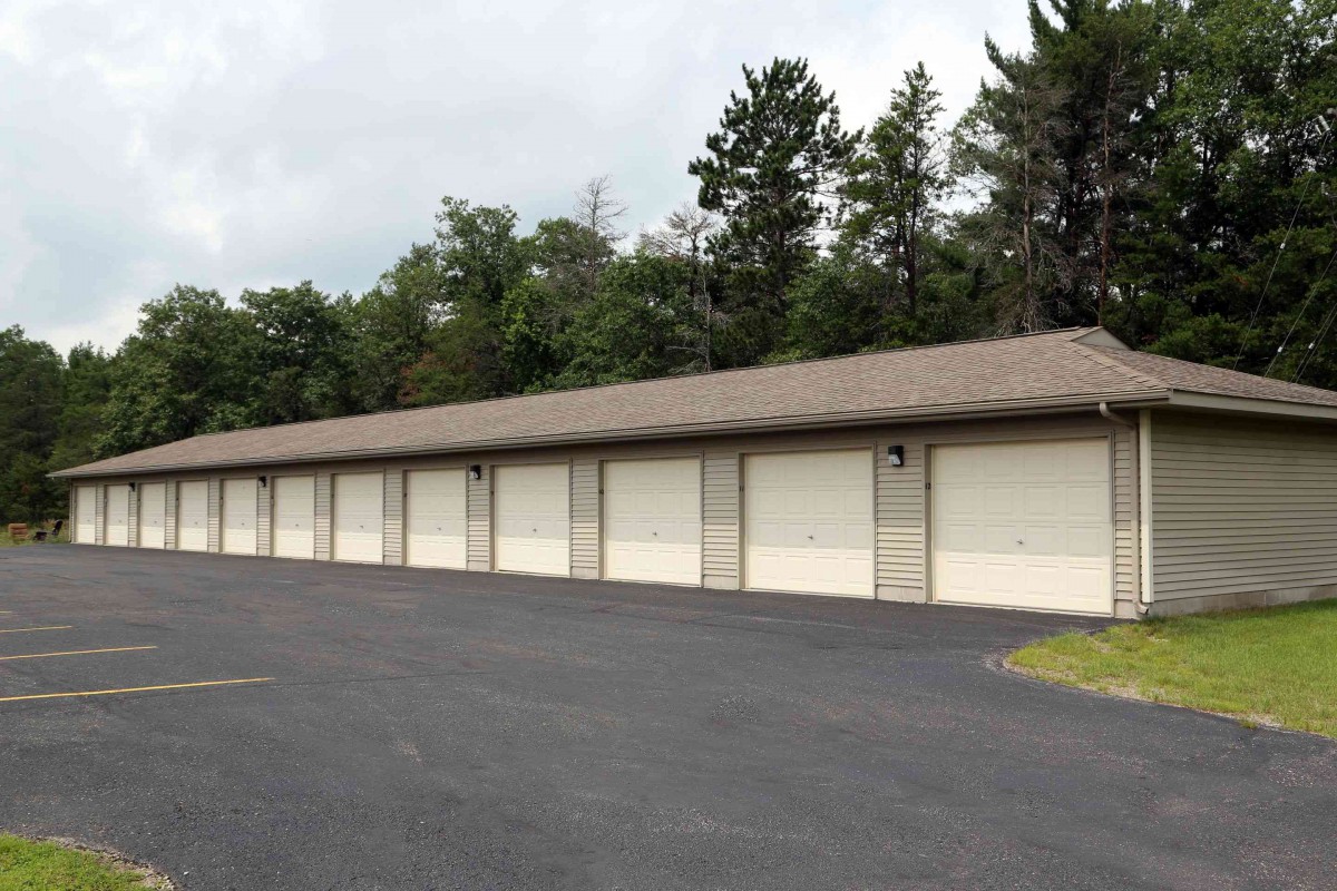 A row of outdoor storage units with closed garage doors on a paved lot.