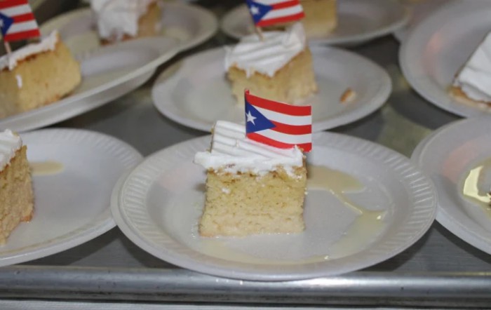 Slices of tres leches cake topped with whipped cream and small Puerto Rican flags.