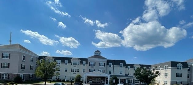 A large white building under a clear blue sky with fluffy clouds.