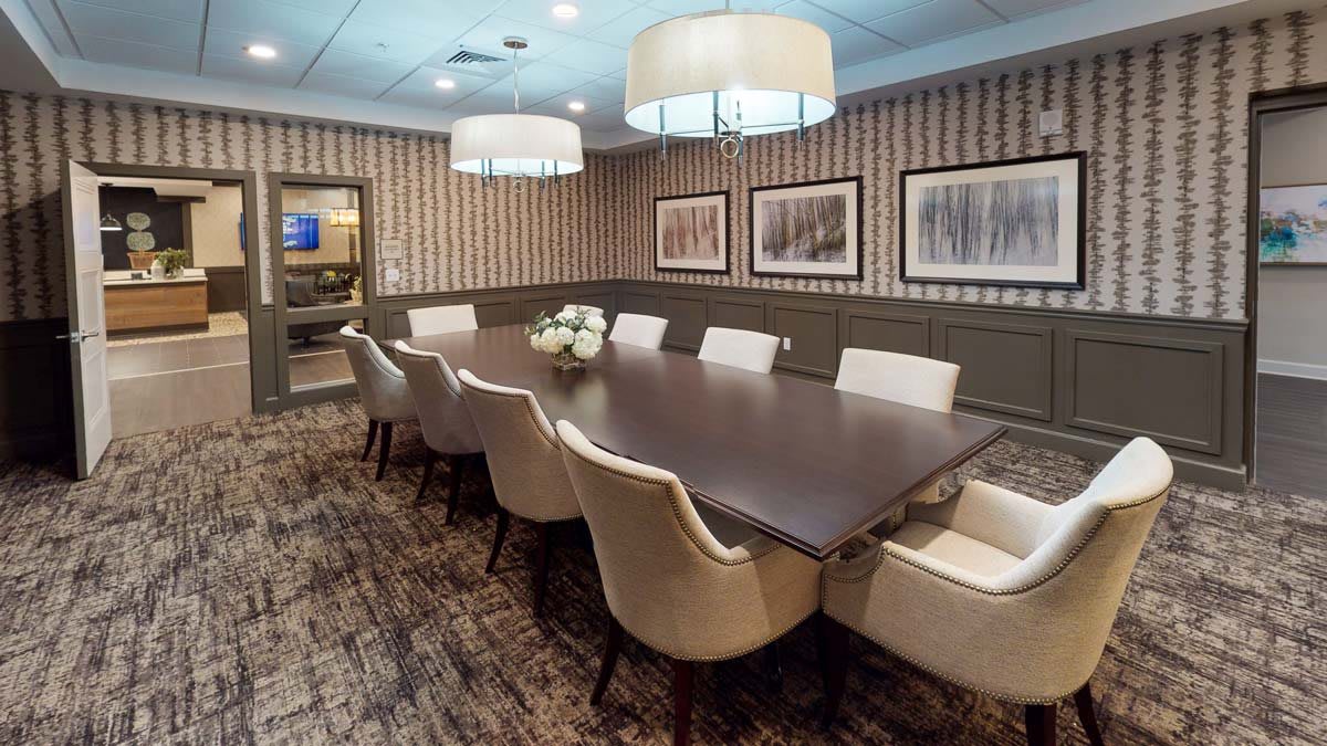 A well-appointed conference room featuring a large table, comfortable chairs, elegant lighting, and tasteful wall art.