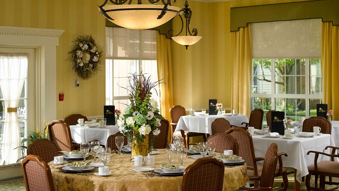An elegantly decorated restaurant dining room with set tables and floral arrangements.
