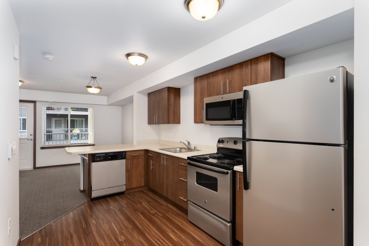 A modern kitchen featuring stainless steel appliances and wood flooring.
