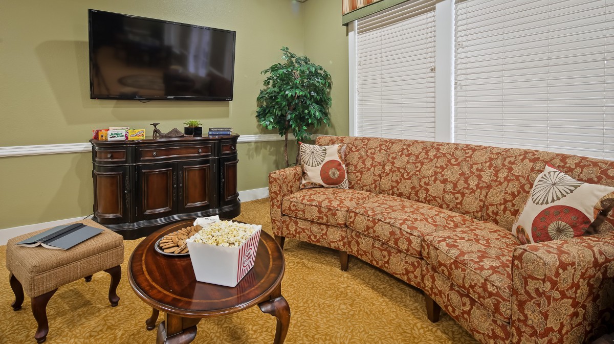 A cozy living room with a patterned sofa, TV, and popcorn on the coffee table.