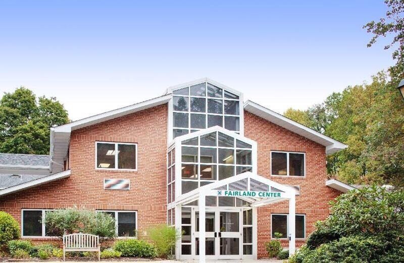 A brick building with a prominent glass entrance and multiple windows.