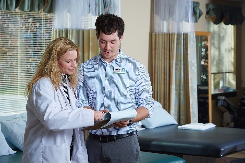 A doctor and a colleague reviewing medical documents in a healthcare setting.