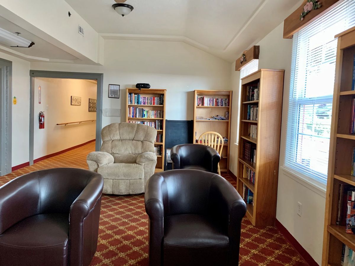 A cozy library reading area featuring comfortable chairs and bookshelves filled with books.