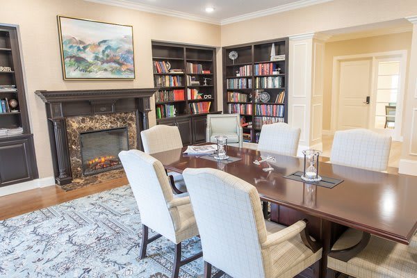 A well-appointed conference room with bookshelves, a fireplace, and seating for six.