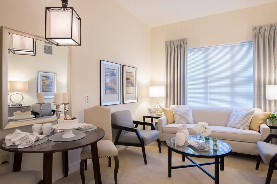 A stylish and modern living room interior featuring a cozy sofa, round glass coffee table, and elegant lighting.