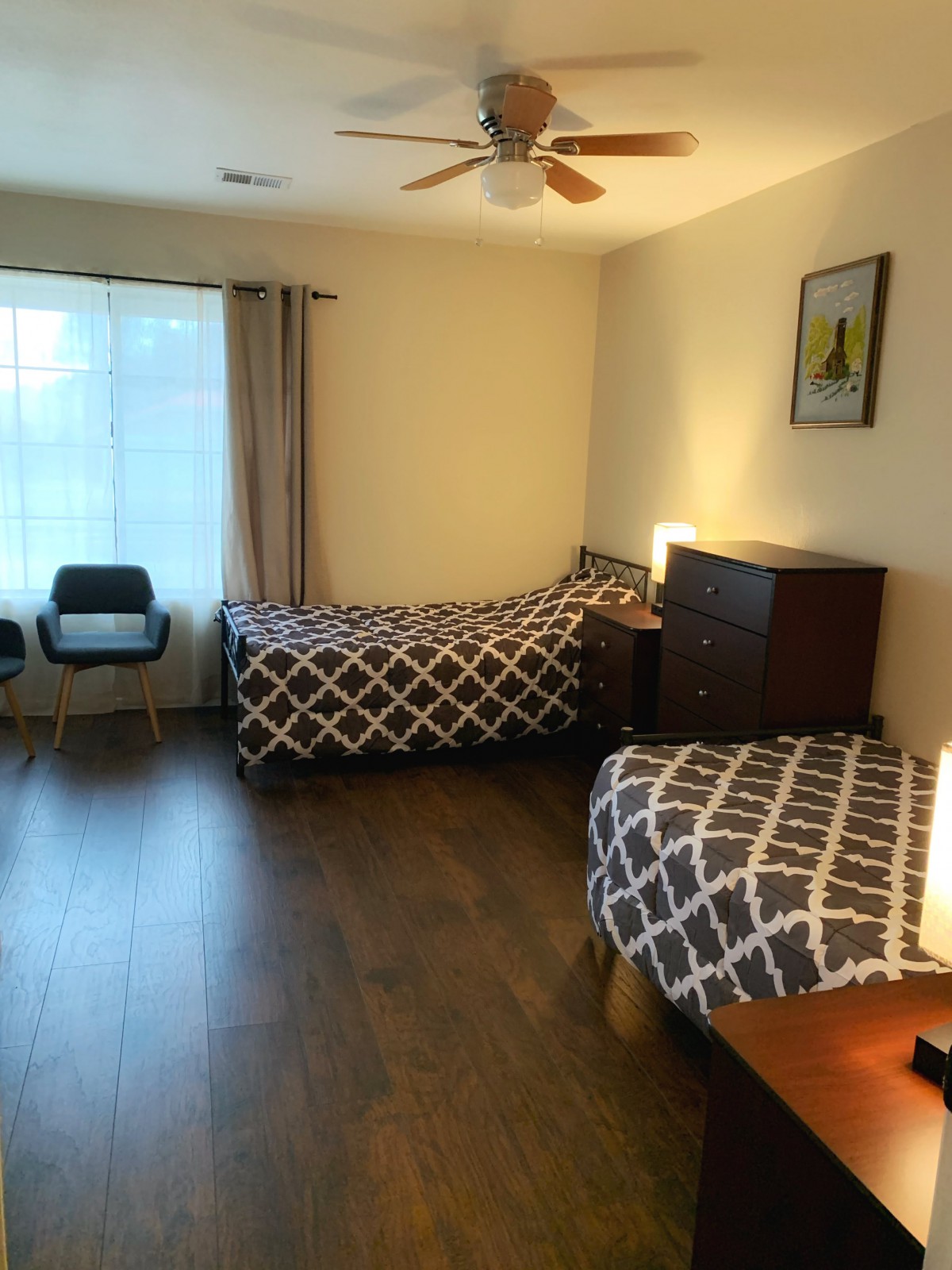 A tidy bedroom with two single beds and wooden flooring.