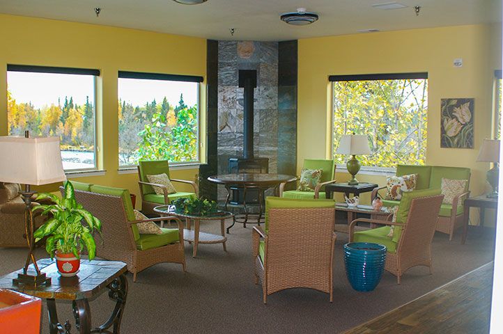 A cozy indoor lounge area with wicker furniture and large windows providing natural light.