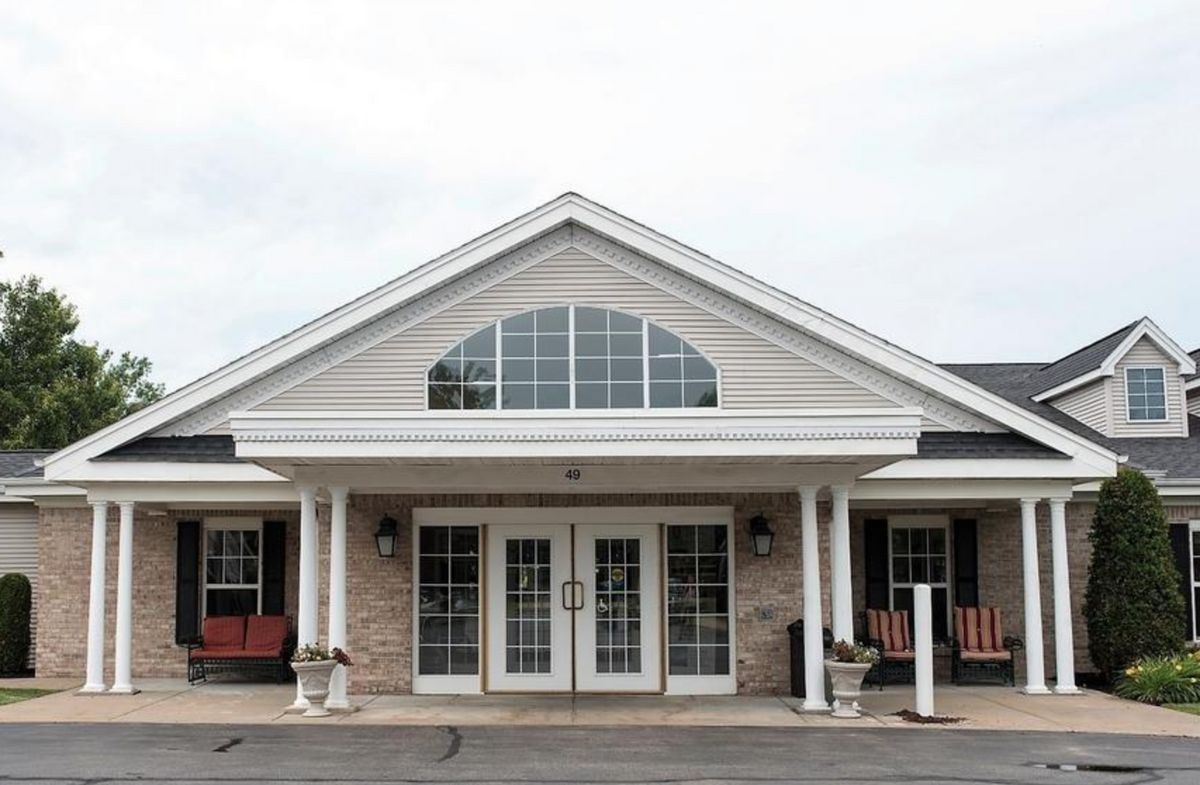 A front view of a building with a gabled roof, large windows, and double glass doors.