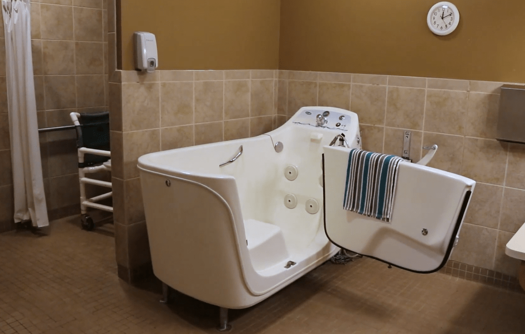 A specialized bathtub designed for hydrotherapy and accessibility, featuring a door for easy entry in a tiled bathroom setting.