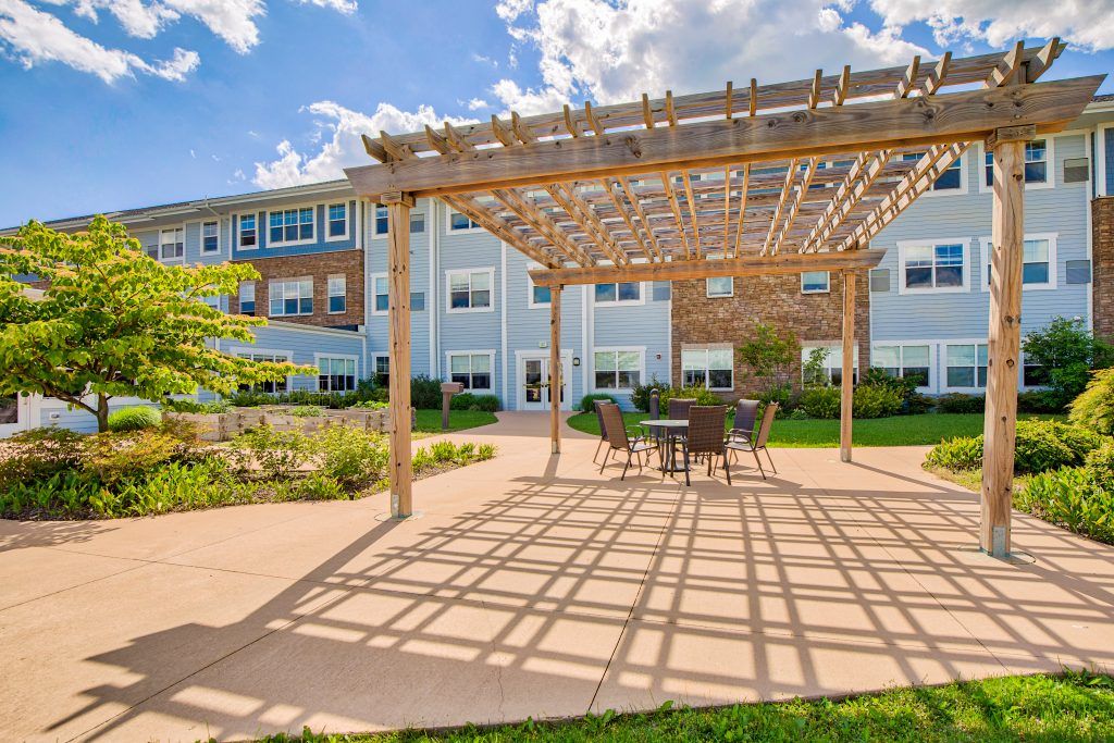A beautiful outdoor patio area with a pergola and seating, adjacent to a modern building on a sunny day.