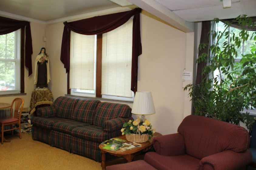 A cozy living room with a sofa, armchair, and a lamp next to the window.