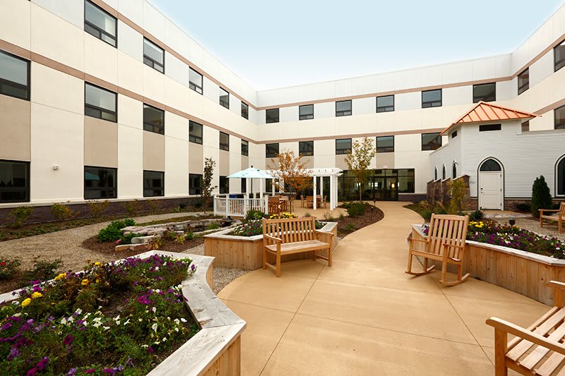 A serene courtyard featuring benches and well-maintained landscaping surrounded by a multi-story building.