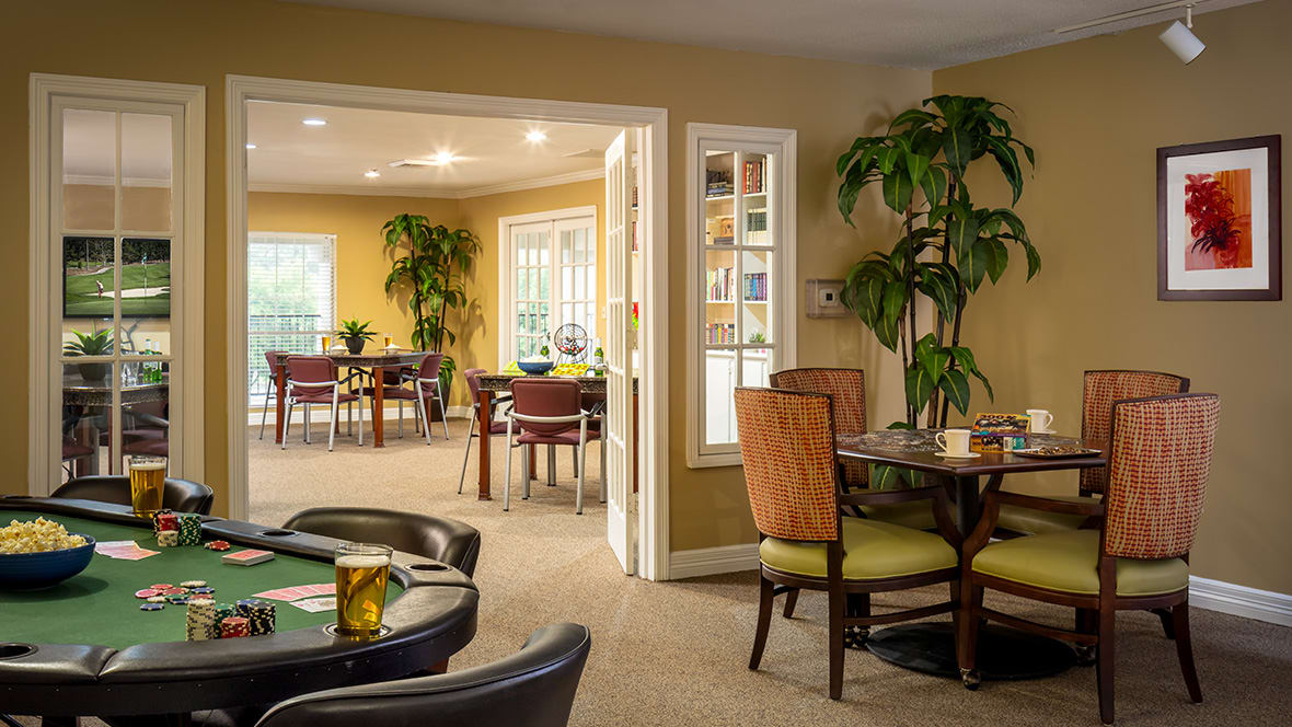 A cozy dining area with multiple tables and chairs, decorated with indoor plants.