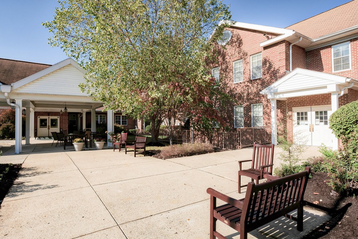 A sunny courtyard with benches and trees outside a building.