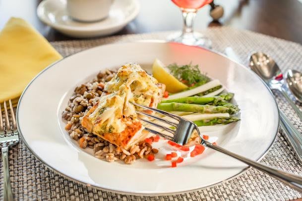 A delicious meal of salmon fillet served with asparagus, rice, and lemon wedges.