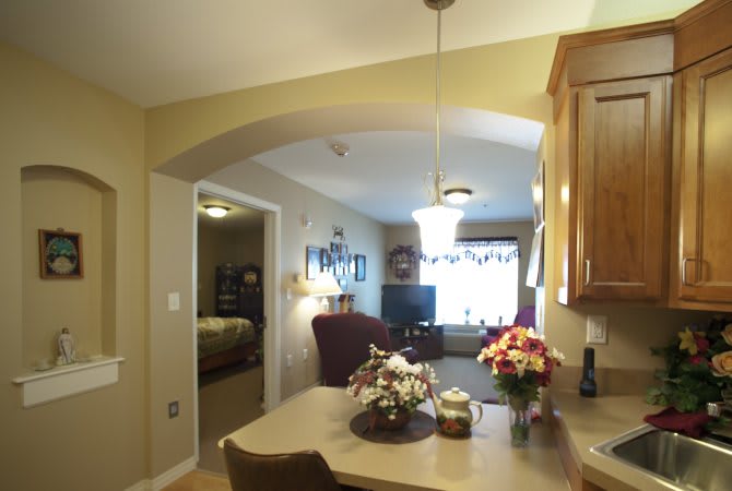 A cozy interior space featuring a kitchen and dining area overlooking a living room with floral decorations.