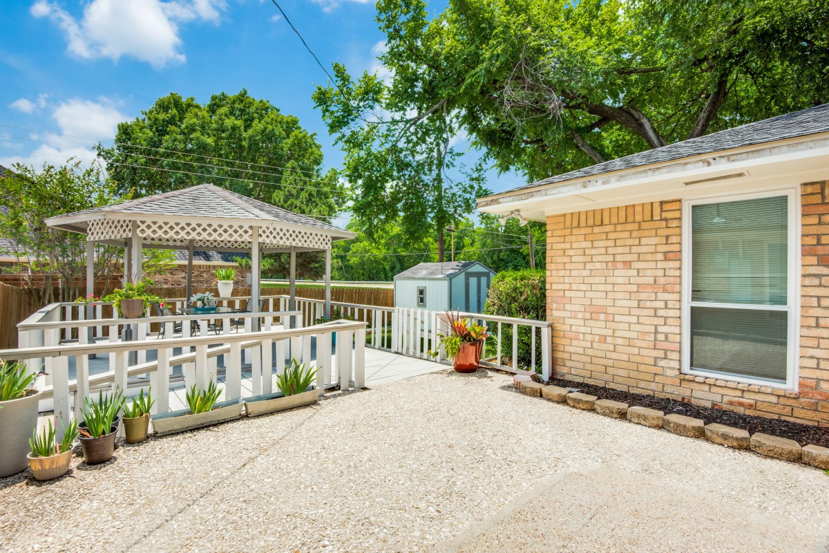 A bright backyard with a gazebo, patio area, and surrounding trees.