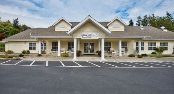 A storefront building with pillars and a parking lot.