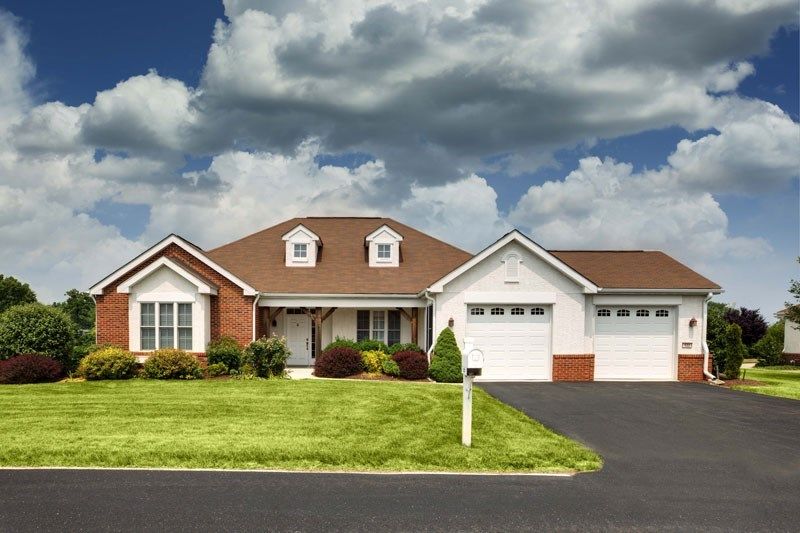 A suburban house with a well-maintained lawn and driveway under a cloudy sky.