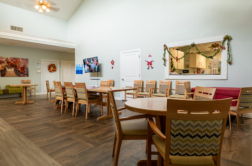 A spacious dining area featuring wooden tables and chairs, complemented by light-colored walls and minimal decorations.