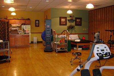 A well-lit rehabilitation therapy room equipped with exercise machines and therapy tools.