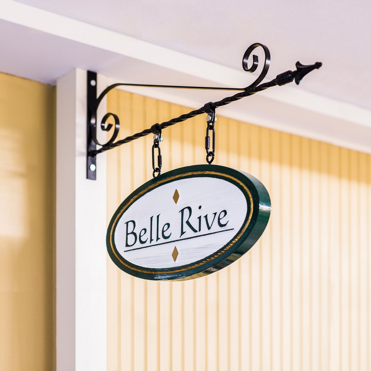 A vintage-style hanging sign reading 'Belle Rive' mounted on a storefront.