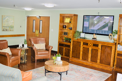 A cozy living room area featuring comfortable seating, wooden furniture, and decorative plants.