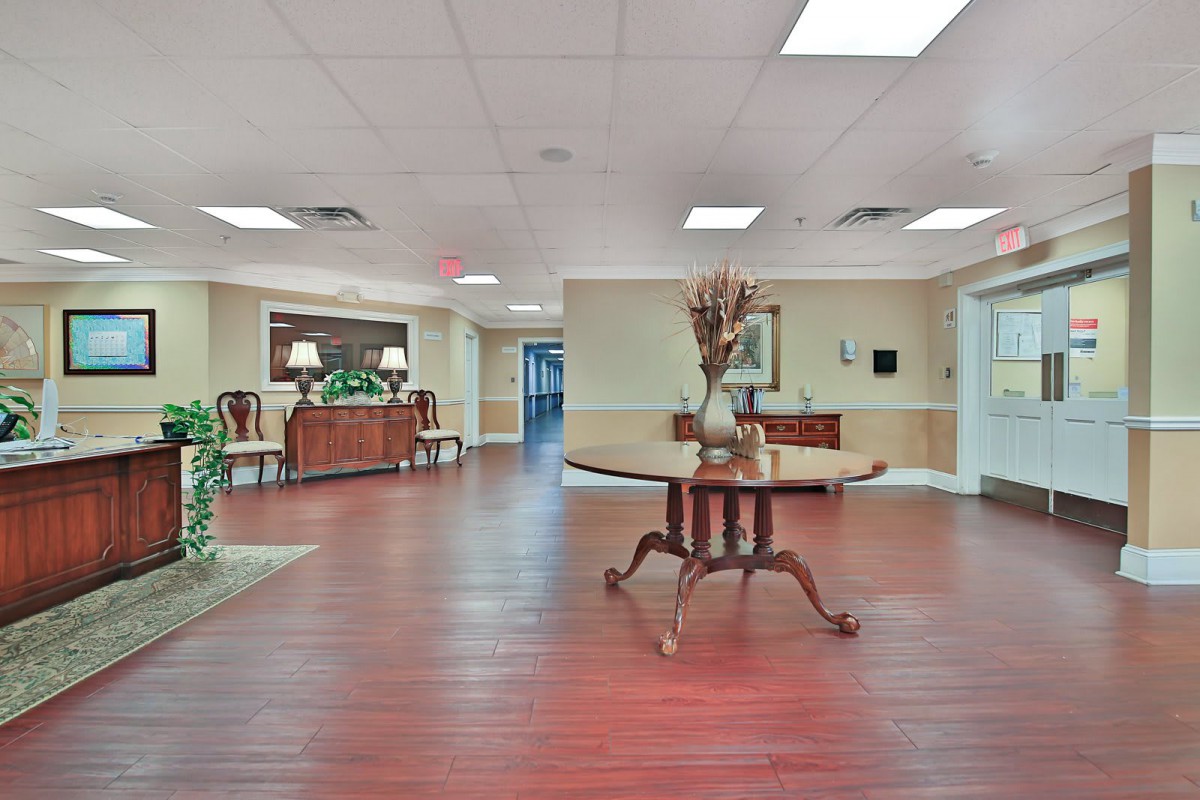 A spacious, well-lit lobby area with wooden flooring and elegant furniture.