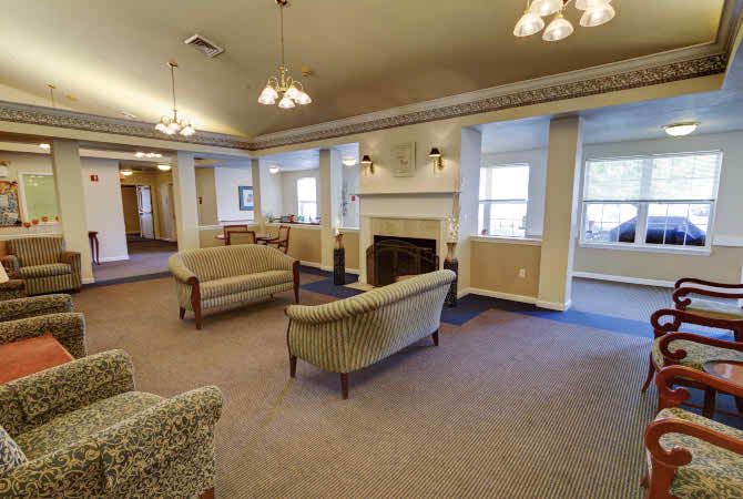 A cozy lounge area featuring sofas and a fireplace, with large windows allowing natural light to fill the room.