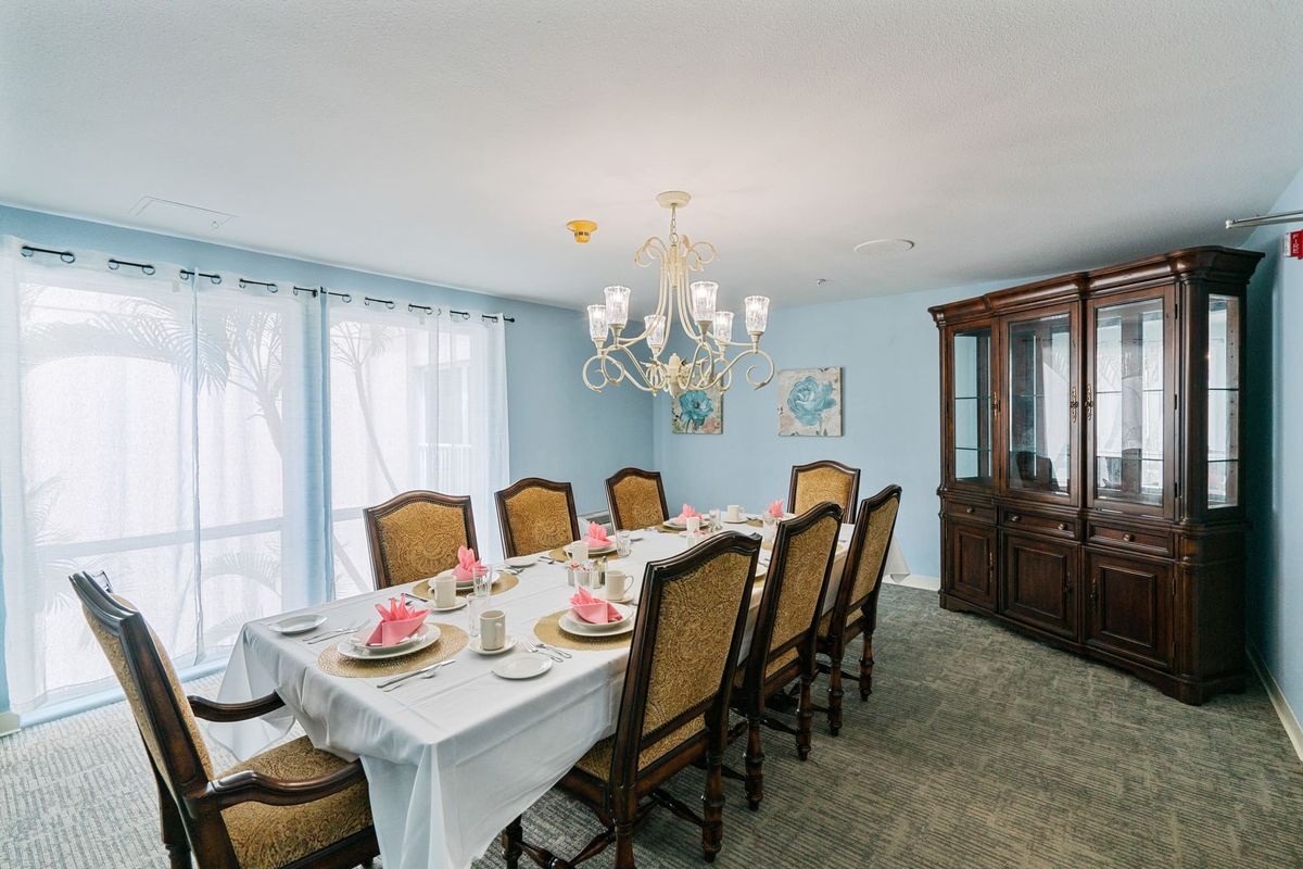 An elegantly set dining room with a chandelier and a china cabinet.