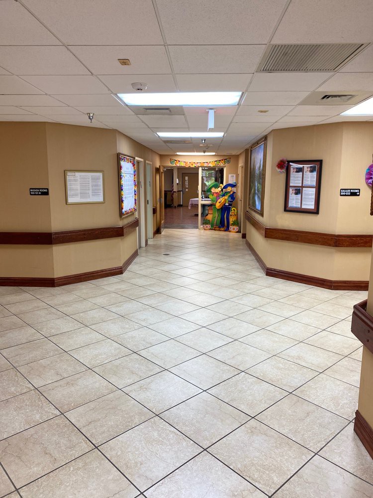 A hospital corridor with tiled floors and bright lighting.